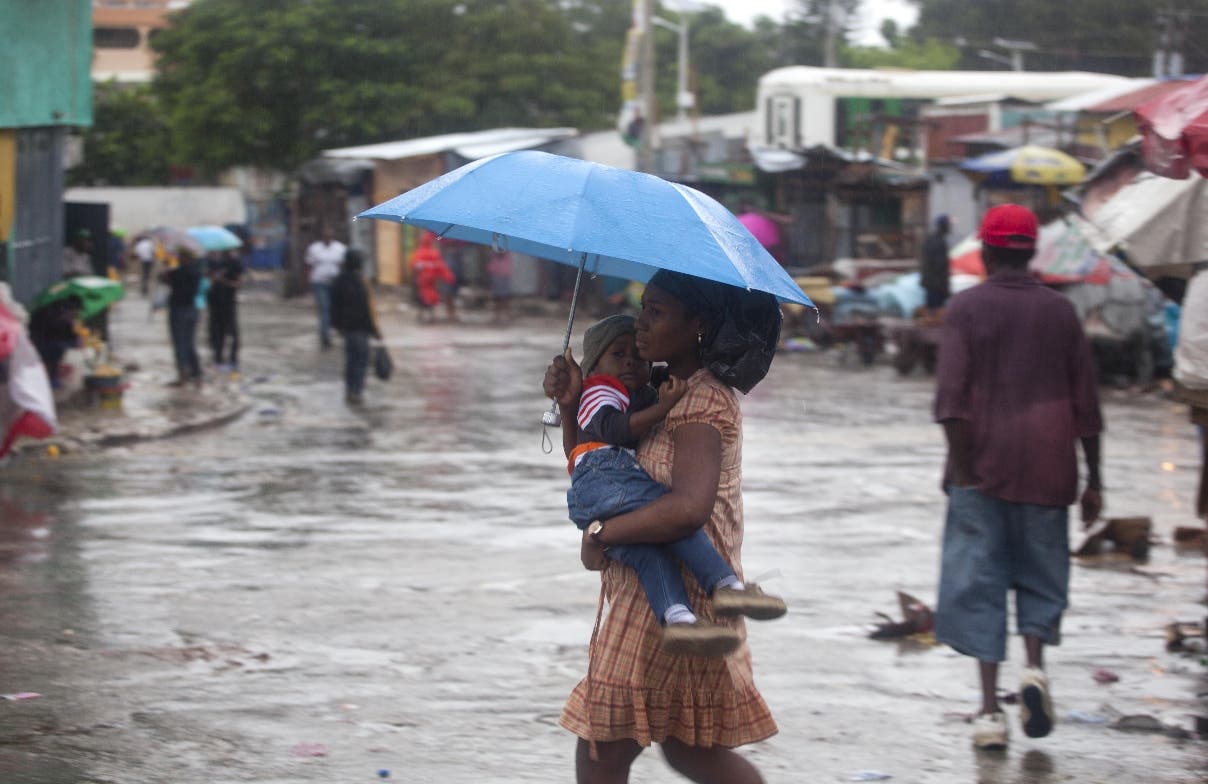 A woman carrying a child walks in the rain triggered by Hurricane Matthew in Port-au-Prince, Haiti, Tuesday, Oct. 4, 2016. Hurricane Matthew roared into the southwestern coast of Haiti on Tuesday, threatening a largely rural corner of the impoverished country with devastating storm conditions as it headed north toward Cuba and the eastern coast of Florida. (AP Photo/Dieu Nalio Chery)