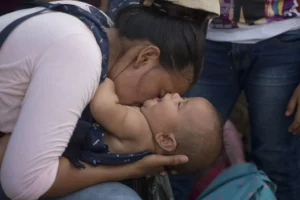 Daisy Zúñiga, una migrante de Puerto Cortez, Honduras, juega con su hijo de 4 meses, Glinder, en Chiquimula, Guatemala, el 16 de octubre de 2018. Zúñiga forma parte de una caravana con unos 2.000 migrantes que esperan entrar a Estados Unidos. El grupo sigue su avance por Guatemala mientras el presidente Donald Trump amenazó con cortar la ayuda a los países centroamericanos que no la frenen. (AP Foto/Moisés Castillo)