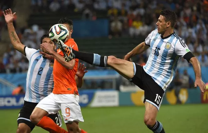 (From L-R) Argentina’s defender Ezequiel Garay , Netherlands’ forward and captain Robin van Persie and Argentina’s defender Martin Demichelis vie for the ball during the semi-final football match between Netherlands and Argentina of the FIFA World Cup at The Corinthians Arena in Sao Paulo on July 9, 2014. AFP PHOTO / ODD ANDERSEN