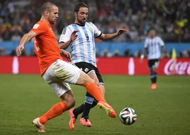 Netherlands' defender Ron Vlaar (L) and Argentina’s forward Gonzalo Higuain vie for the ball during the semi-final football match between Netherlands and Argentina of the FIFA World Cup at The Corinthians Arena in Sao Paulo on July 9, 2014.  AFP PHOTO / FABRICE COFFRINI