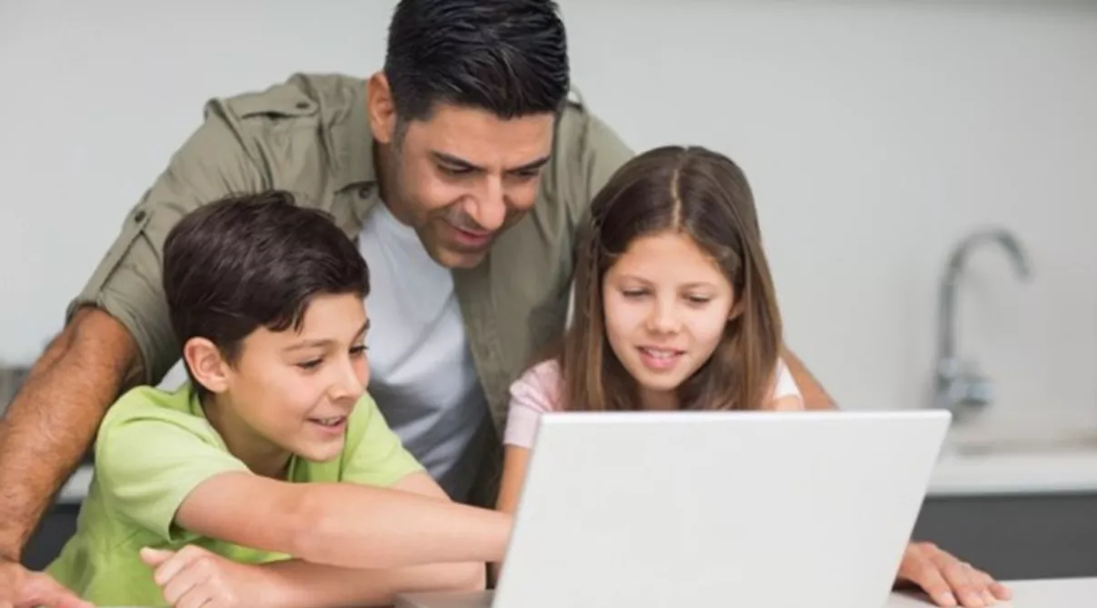 Father with young kids using laptop in kitchen