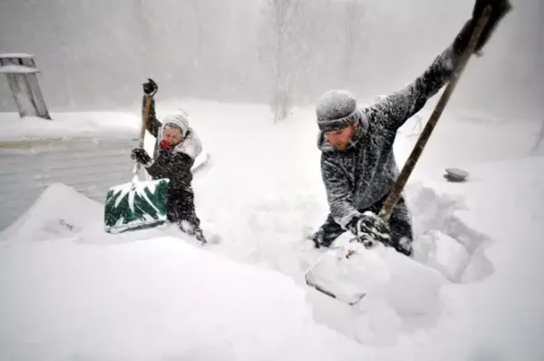 BUFFALO, NY – NOVEMBER 20, 2014: Tami Normile and Richard Brooks attempt to remove some of the five feet of snow from a roof top on November 20, 2014 in the Lakeview neighborhood of Buffalo, New York.The record setting Lake effect snowstorm dumped up to six feet of snow in less than 24 hours closing a one hundred mile section of The New York State Thruway as well as other major roads around Buffalo. Seven deaths have already been attributed to the storm and a second round beginning late Wednesday evening will bring up to three more feet of snow overnight and into Thursday.   John Normile/Getty Images/AFP== FOR NEWSPAPERS, INTERNET, TELCOS & TELEVISION USE ONLY ==