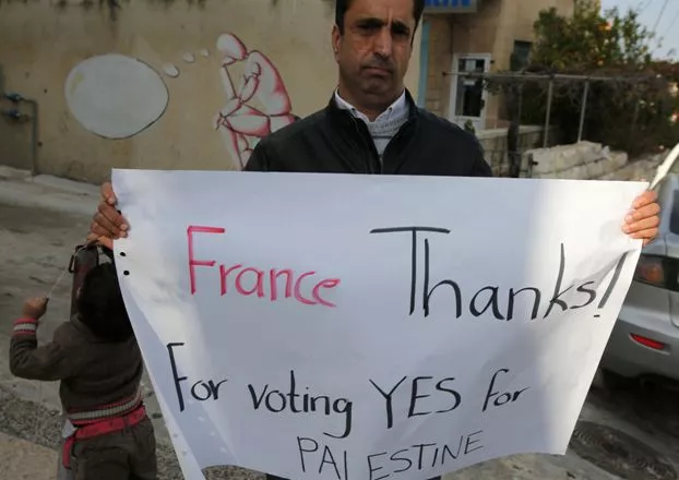 A Palestinian man holds a poster as he calls for France to vote for the recognition of a Palestinian State outside a French and German language training centre in the West Bank city of Ramallah on December 2, 2014. French lawmakers were poised to recognise Palestine as a state, following similar moves in Britain and Spain that reflect growing European frustration with the stalled Middle East peace process. AFP PHOTO / ABBAS MOMANI