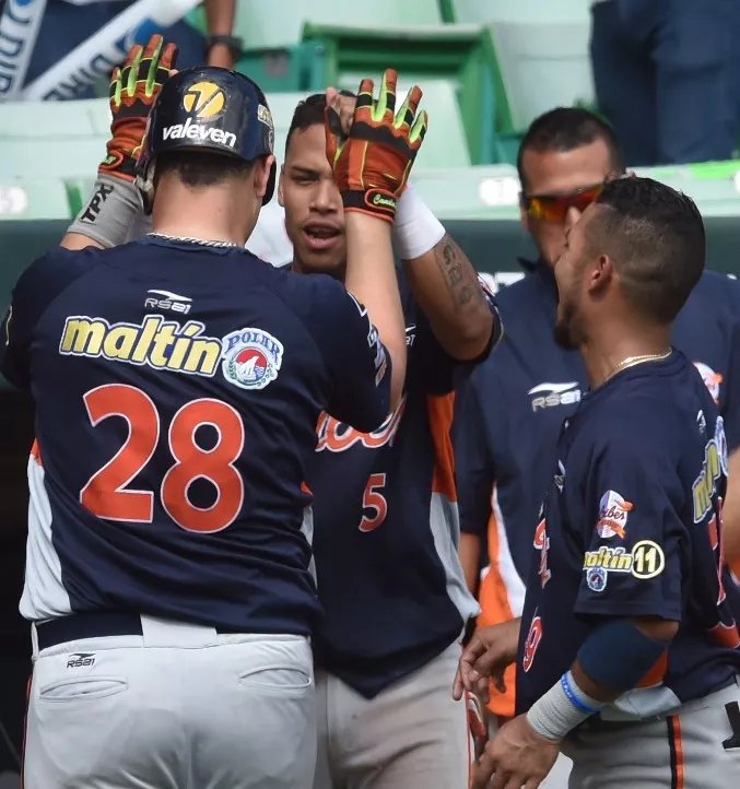 Venezuela National baseball infielder Ballbino Rafael Fuenmayor(28)  is high fived by team mate Orlando Arcia(5) after his 6th inning home run to make the score 5-1 over the Cuban National baseball team during the Serie Del Caribe February 5, 2015 in San Juan, Puerto Rico.  AFP PHOTO/PAUL  J. RICHARDS