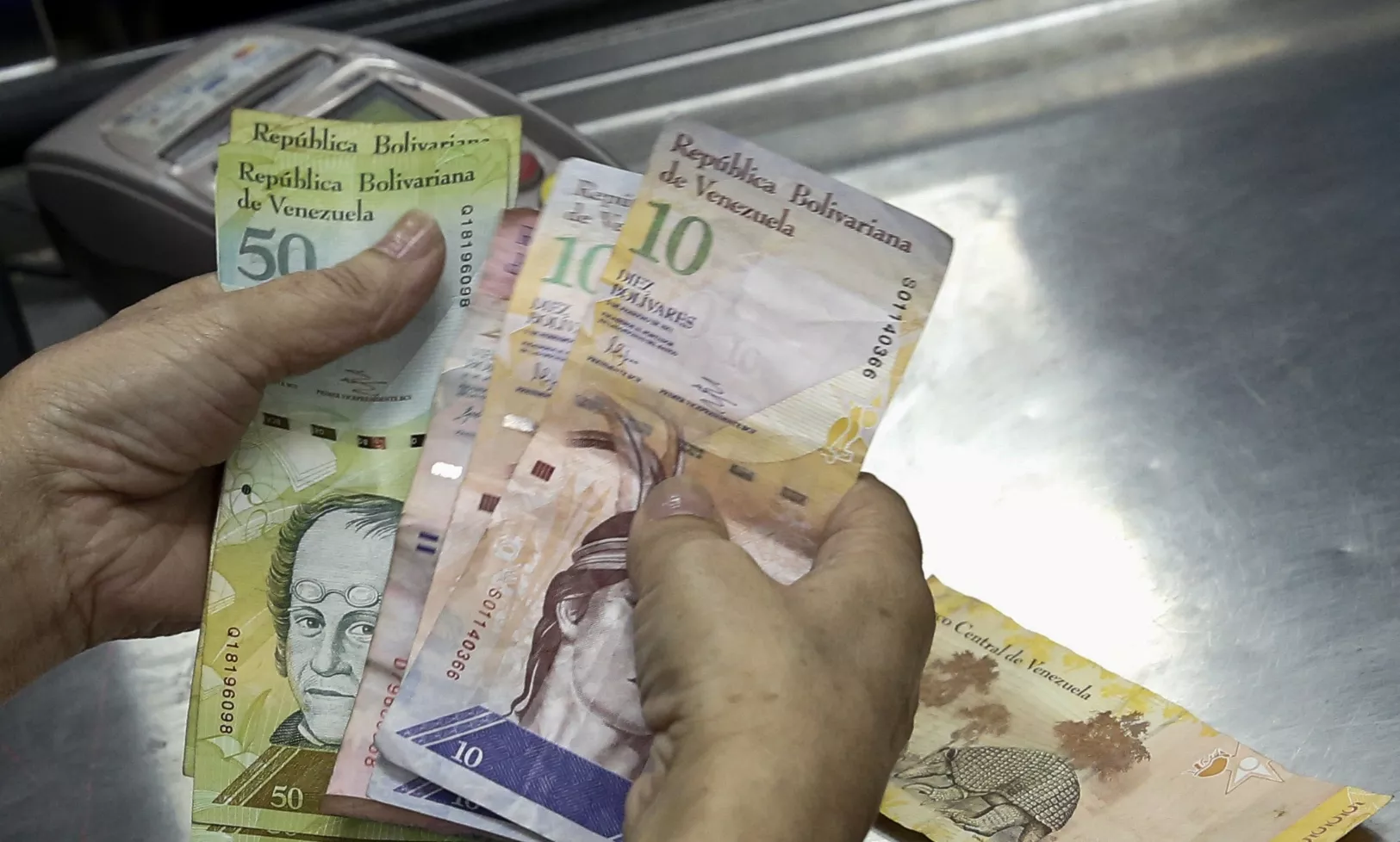A cashier counts Venezuelan bolivar notes at a supermarket checkout line in Caracas