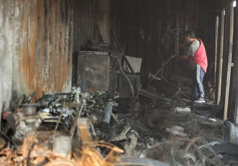 A man works cleaning the damage caused by the forest fire on a car workshop in the Roderillo neigborhood in Valparaiso, Chile, on March 14, 2015. Chile declared a state of emergency Friday and ordered the evacuation of up to 16,000 people as a raging forest fire led to at least one death and threatened the historic port city of Valparaiso. AFP PHOTO/Vladimir Rodas