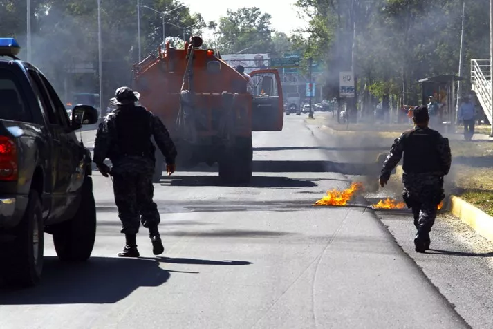 Firefighters  and members of the state police rush to put out petrol bombs on fire on the Gomez Morin Avenue in Guadalajara, Jalisco state, Mexico, on May 1, 2015. Criminals burnt simultaneously several robbed vehicles to block at least four accesses to Guadalajara, the second largest city of Mexico, informed authorities of the state of Jalisco. AFP PHOTO/Hector Guerrero