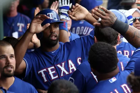 Carlos Peguero mientras es felicitado tras conectar uno de sus dos jonrones. Foto: Texas Rangers.