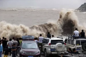 People gather on the bank to watch huge waves as typhoon Chan-hom comes near Wenling, east China's Zhejiang province on July 10, 2015. Typhoon Chan-hom lashed Japan's Okinawa island chain on July 10 as it pushed towards Taiwan and onto China, leaving more than 20 people injured. CHINA OUT   AFP PHOTO