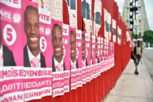 Estudiantes pasan frente a una pared con afiches de varios de los 54 candidatos presidenciales.