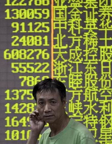 An investor walks in front of an electronic screen showing stock information at a brokerage house in Hangzhou