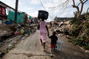 Una mujer camina hacia un refugio con su hijo, el domingo 9 de octubre de 2016, después de que su casa en Jeremie, Haití fue destruida por el huracán Matthew. (AP Foto/Dieu Nalio Chery).