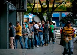 Venezolanos hacen fila para comprar pan en una panadería de Caracas.