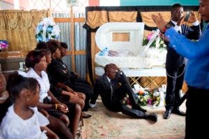 En esta imagen, tomada el 1 de abril de 2017, un hombre se sienta junto al ataúd con los restos de su madre durante un funeral en la iglesia de Santa Ana, en Puerto Príncipe, Haití. AP