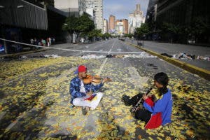  Los músicos juegan sus instrumentos mientras se sientan en medio de una carretera llena de boletos de metro en una barricada instalada por manifestantes anti-gobierno en Caracas, Venezuela. AP