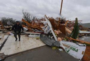 Un oficial de policía busca a sobrevivientes entre casas destruidas después de un fuerte daño 