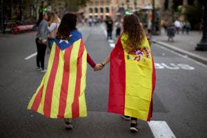 Irene Guszman, de 15 años, con una bandera española en sus hombros, y Mariona Esteve, de 14, con la 'estelada', la bandera Catalana. se dirigen a una manifestación en Barcelona. (AP Photo/Emilio Morenatti, File)