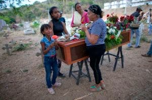 Yajaira Rojas, a la derecha, se para junto al ataúd con los restos de su hijo Alix Eduardo Díaz en el Cementerio Municipal de Valencia, Venezuela, el viernes 30 de marzo de 2018. Algunas de las 68 víctimas fatales que dejó el devastador incendio en las celdas de una comisaría fueron enterradas una al lado de otra en medio del reclamo de sus familiares que exigen justicia y la verdad sobre una de las mayores tragedias carcelarias del país suramericano. (AP Foto/Ariana Cubillos)