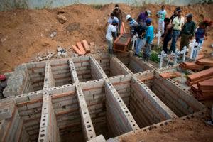 Familiares llevan el ataúd con los restos de José Manuel Pérez, de 28 años, para depositarlo en una serie de nichos de ladrillos que fueron construidos uno a lado del otro en un área del Cementerio Municipal de Valencia, Venezuela, el viernes 30 de marzo de 2018. Algunas de las 68 víctimas fatales que dejó el devastador incendio en las celdas de una comisaría fueron enterradas una al lado de otra en medio del reclamo de sus familiares que exigen justicia y la verdad sobre una de las mayores tragedias carcelarias del país suramericano. (AP Foto/Ariana Cubillos)