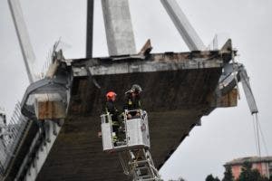 Bombero inspecciona el sitio del puente de la carretera Morandi colapsado en Génova, norte de Italia, el martes 14 de agosto de 2018. Una gran parte del puente se derrumbó sobre una zona industrial en la ciudad italiana de Génova durante una tormenta repentina y violenta, dejando a los vehículos aplastado en escombros a continuación. (Luca Zennaro / ANSA vía AP)