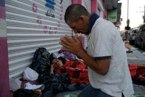 Marvin Sanabria, uno de los cientos de migrantes que  participa en la caravana, reza después de dormir a la intemperie. (AP Photo/Moises Castillo)