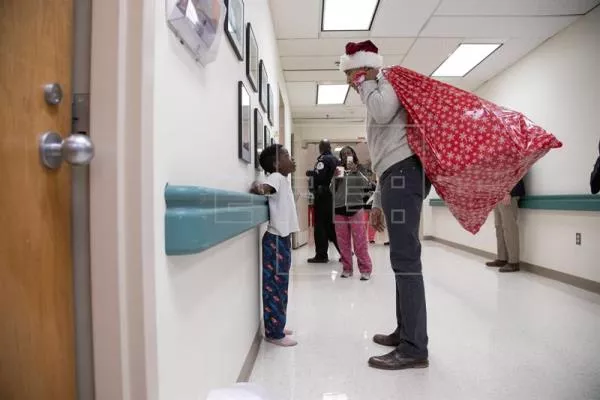 Obama entrega regalos a niños enfermos vestido con gorro y saco de Papa Noel