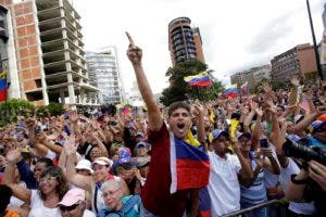 Manifestantes contra el gobierno celebran después de que el líder opositor Juan Guaidó se declarara presidente "encargado" de Venezuela en un evento en el que se pidió la renuncia del mandatario Nicolás Maduro en Caracas, Venezuela, el miércoles 23 de enero de 2019. (AP Foto/Boris Vergara)