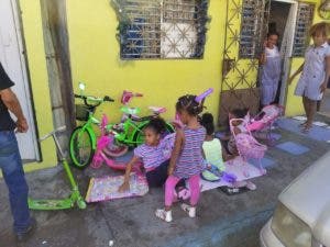 Niños disfrutan de sus juguetes frente a su hogar.