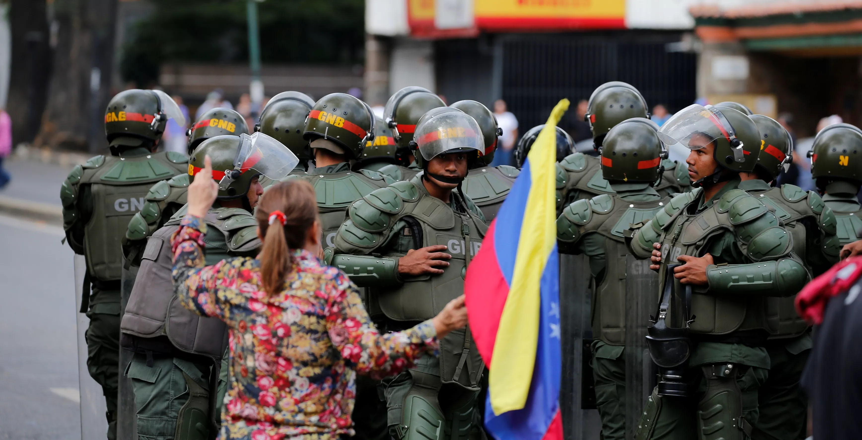 5. Una mujer con una bandera nacional venezolana obstruye a los miembros de la Guardia Nacional Bolivariana bloqueando el paso de miembros de la oposición durante una marcha de protesta contra el presidente Nicolás Maduro en Caracas.