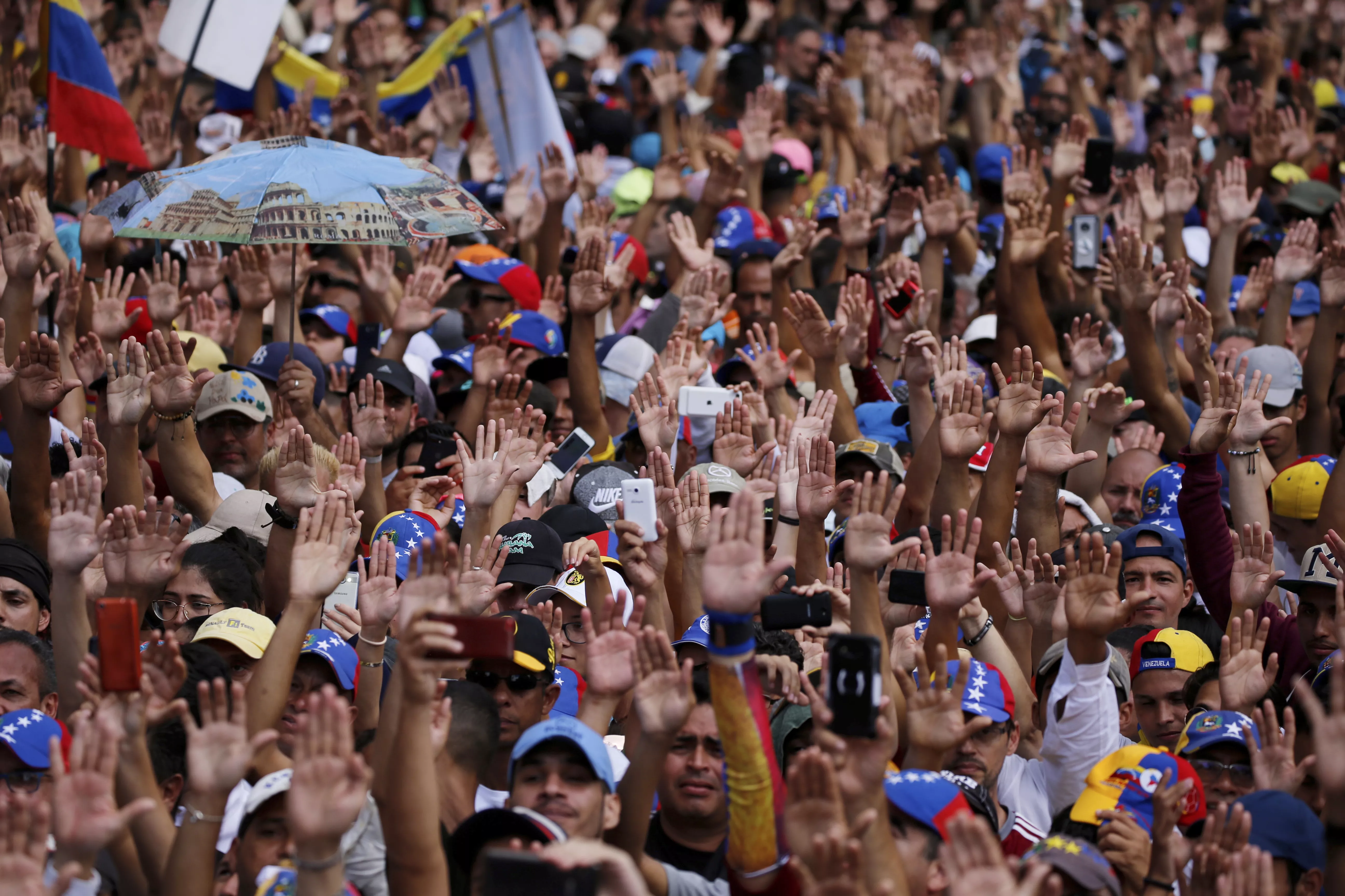 7. Los manifestantes en contra del gobierno levantan sus manos durante el juramento simbólico de Juan Guaido, jefe del congreso de oposición, quien se declaró a sí mismo presidente interino de Venezuela. AP