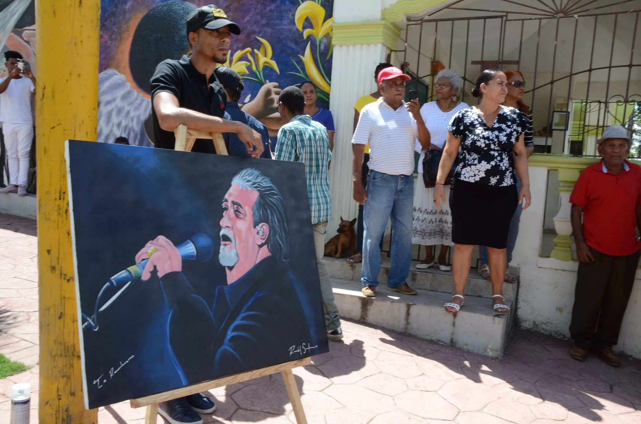 7. Un joven muestra una pintura con la imagen de Anthony Ríos durante entierro.