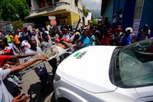 Manifestantes llevan el cuerpo del hombre a un vehículo de la policía, gritando culpables a la policía por su muerte, durante una protesta antigubernamental en Puerto Príncipe, Haití, el domingo 9 de junio de 2019. Manifestantes que denuncian la corrupción paralizaron gran parte de la capital. ya que exigieron la destitución del presidente Jovenel Moise. AP 