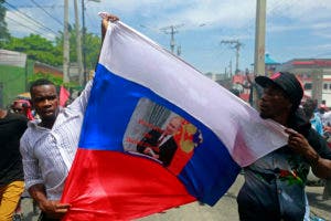 Los manifestantes antigubernamentales sostienen una bandera rusa con una foto del presidente ruso, Vladimir Putin, que se lee en creole "Larga vida a Putin. Abajo Donald Trump" en Puerto Príncipe, Haití. AP