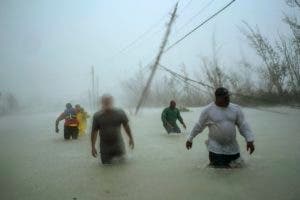 Voluntarios caminan por una calle inundada y bajo el viento y la lluvia del huracán Dorian mientras tratan de rescatar familias cerca del puente Causarina en Freeport, Gran Bahama, el martes 3 de septiembre de 2019. (Foto AP/Ramón Espinosa)