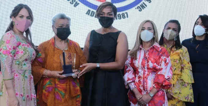 Wendy Santos de Díaz, presidenta de Adeofa entrega la distinción.