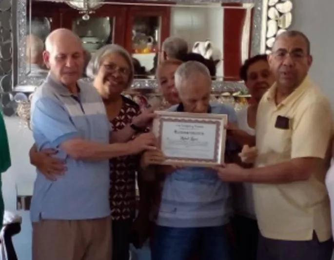 Foto, en el centro, Rafael López recibe un reconocimiento de periodistas y vecinos.