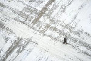 Un hombre cruza la calle S. Sixth St. cubierta de nieve en el centro de Minneapolis, el miércoles 22 de febrero de 2023, en Minnesota, Estados Unidos. (Alex Kormann/Star Tribune vía AP)