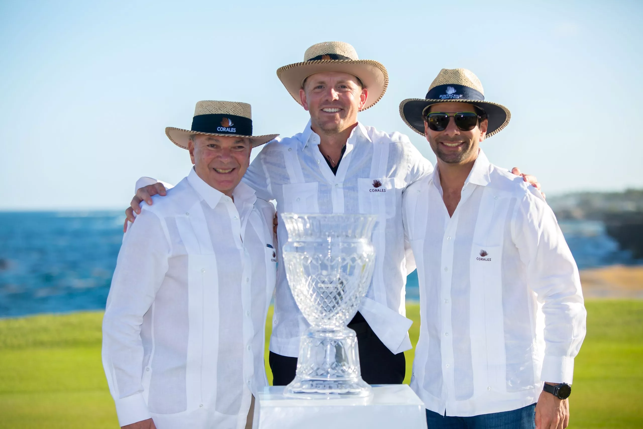 Matt Wallace (centro) recibe el trofeo que lo acredita como el nuevo campeón del PGA Tour. Le acompañan, en los extremos, Frank Elías Rainieri, presidente Grupo Puntacana y Frank Rainieri, fundador y presidente del Consejo Puntacana.