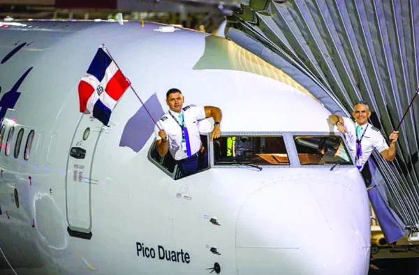 Los pilotos de la nave  Pico Duarte de Arajet ondean ambas banderas,  luego del vuelo inaugural de la ruta hacia Chile.