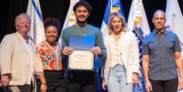 Representantes de ambas entidades entregan el certificado a uno de los jóvenes.