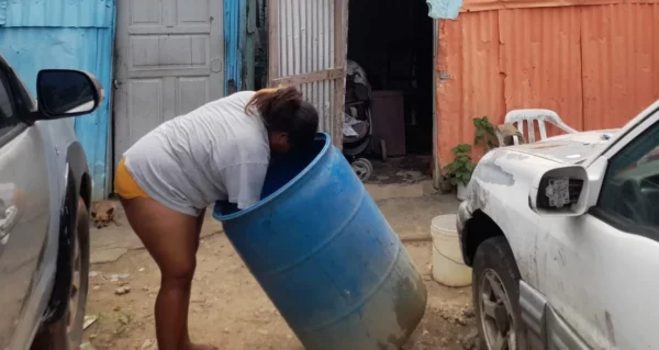 Dama mientras recolecta agua en un tanque de almacenamiento  en un sector de SD.