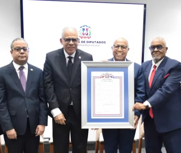 Carlos Manuel Estrella recibe el reconocimiento de manos de Alfredo Pacheco.