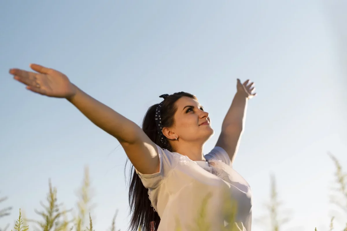 joven-mujer-sosteniendo-sus-brazos-en-el-aire-y-mirando-al-cielo