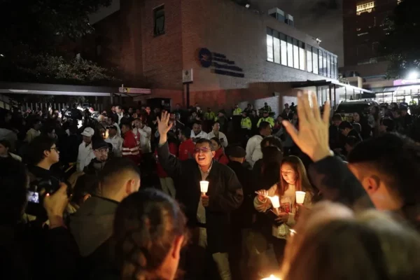 Personas encienden velas a las afueras de la Fundación Santa Fe donde fue trasladado el senador colombiano Miguel Uribe Turbay este sábado, en Bogotá