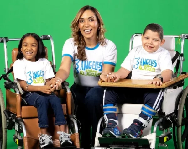 Directiva de la entidad junto a dos niños sobre ruedas.