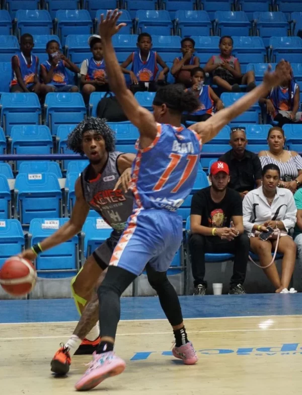 Los Mina-Luis Peña, de los Trenes del Este, es defendido por Bryan Beato, de Caobas City.