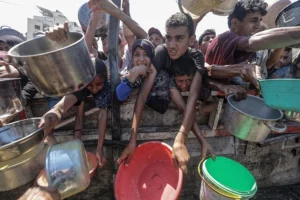 Imagen reciente de palestinos desplazados mientras esperan recibir comida en una cocina benéfica, en la ciudad de Gaza.