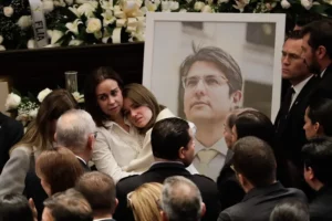 Fotografía del 11 de agosto de 2025 de la esposa del fallecido senador y precandidato a la presidencia de Colombia Miguel Uribe Turbay, Claudia Tarazona (c-i), abrazando a una de sus hijas frente a una fotografía de Miguel.