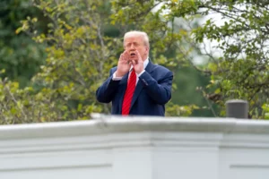 El presidente Donald Trump grita a los reporteros mientras inspecciona los terrenos desde el techo arriba de la columnata que va hacia el Ala Oeste de la Casa Blanca, el martes 5 de agosto de 2025, en Washington.