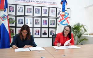 Odile Camilo Vincent, izquierda, y Elizabeth Mena firman el acuerdo entre la ADRU y el Comité Organizador de los Juegos Santo Domingo 2026.